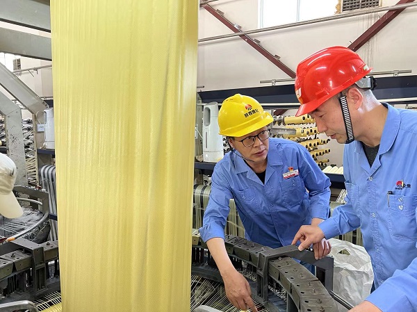 1653620936533051.jpeg 圓織機技術升級改造攻關組在現場研究圓織機潤滑技術照片.jpg